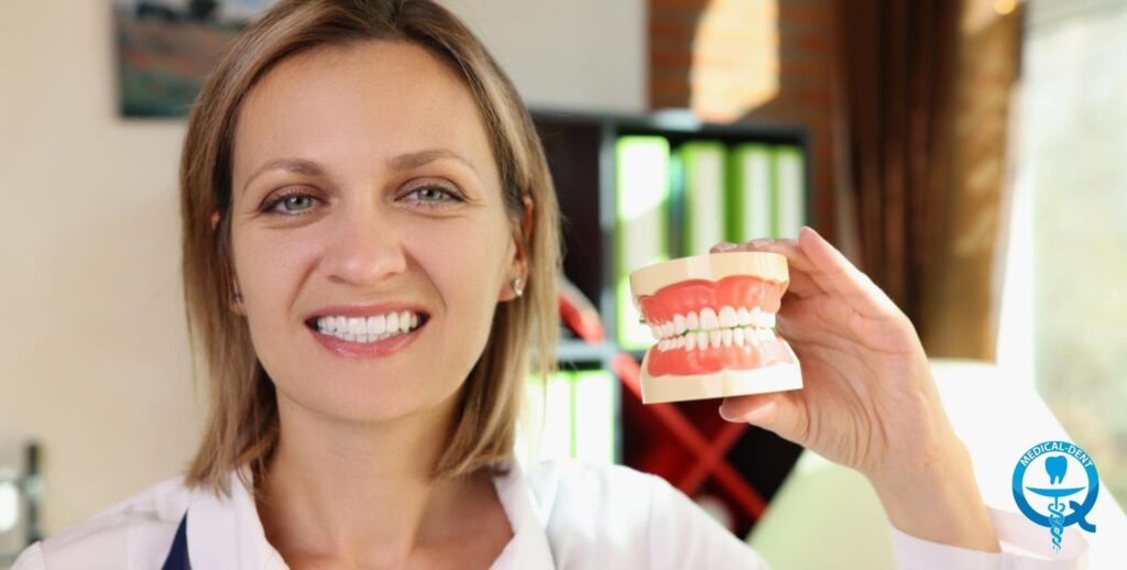 The painting depicts a smiling woman, probably a dentist or someone working in a dental surgery, holding a model of a denture jaw in her hand. A treatment room with dental equipment can be seen in the background. The woman is demonstrating the denture, but her identity has been anonymised to protect her privacy.