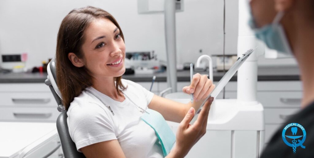 The painting shows a smiling woman in a white apron, probably a dentist, sitting in a chair in a dental office. She is holding a tablet in her hand and looks happy as she works. In the background, blurred figures and the equipment of the surgery can be seen.