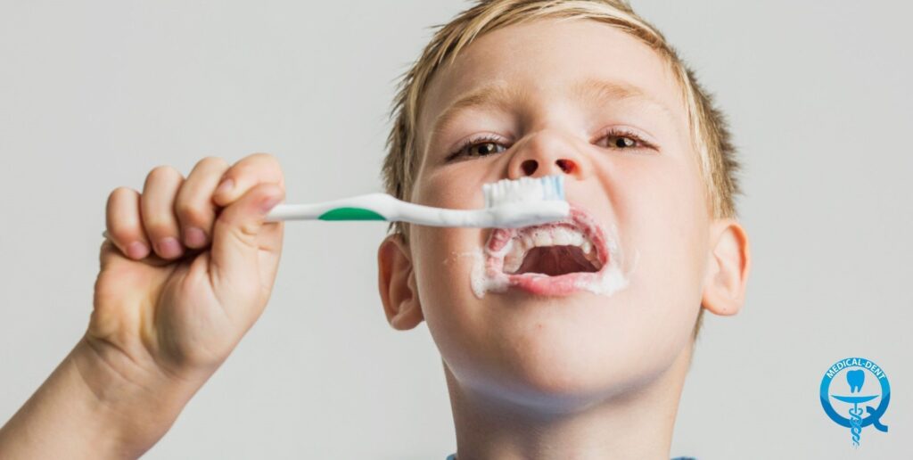 The picture shows a child brushing his teeth. The child has his mouth open and is inserting a toothbrush covered with toothpaste. The photo appears to promote good oral hygiene habits in children.