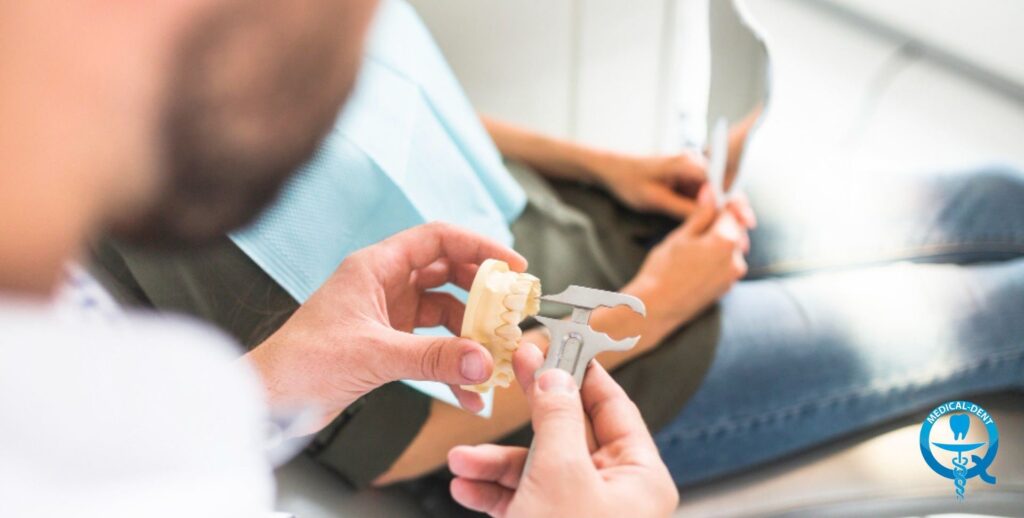 The painting shows the dentist's hands holding a model of the dentition on which a teaching or demonstration of dental procedures is being carried out. Also visible are medical documents in the hands of the dentist. The photograph does not reveal the identity of the subjects.